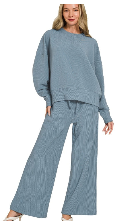 Model wearing a blue ribbed sweater and pants set on a white background