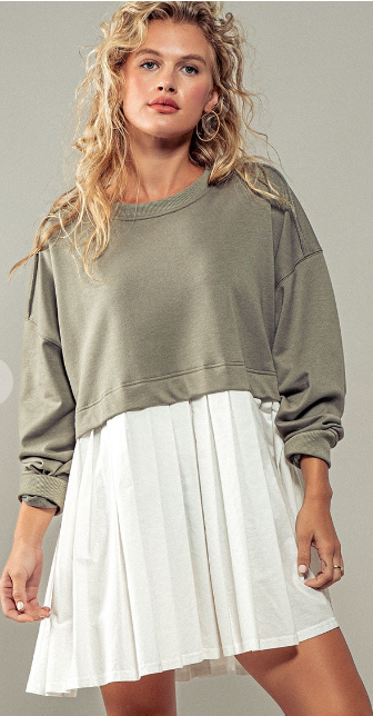 Model wearing a green ribbed knit sweater and a white pleated mini dress.