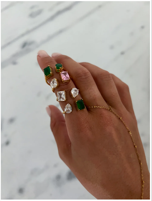 A collection of gold rings with different colored gemstones on a person's hand.